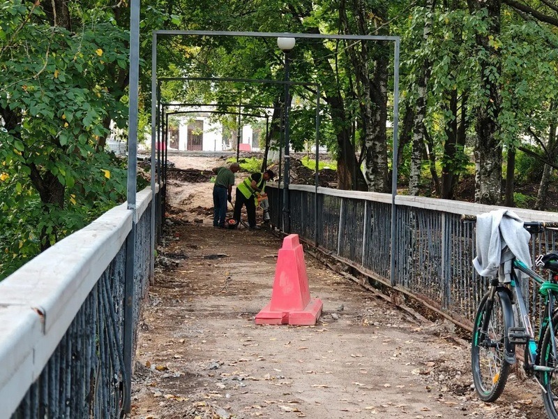 Двое рабочих демонтируют ограждение на мосту через Золотуху..